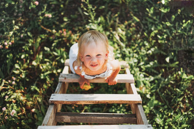 Portrait of cute smiling girl standing on ladder