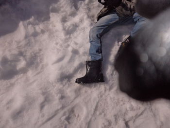 Low section of man standing on snow covered beach