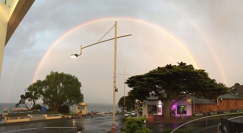 Rainbow over road against cloudy sky