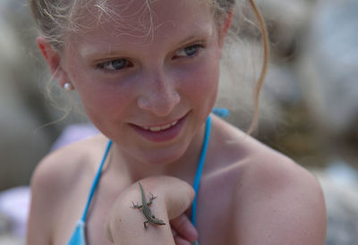 Close-up portrait of smiling girl with tiny lizard