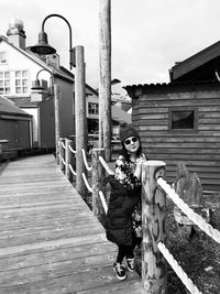 Portrait of woman standing by railing on footpath