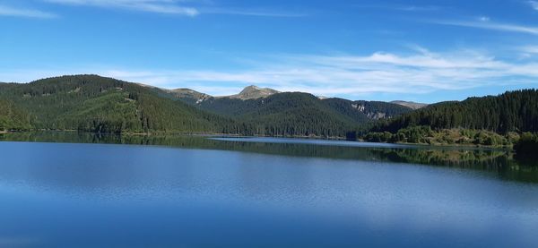 Scenic view of lake by mountains against blue sky