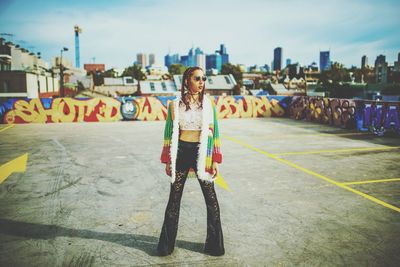 Fashionable young woman standing at parking lot in city