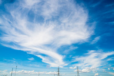 Low angle view of electricity pylon against blue sky