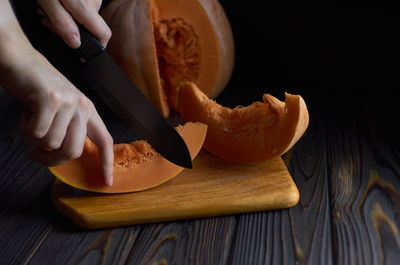 Cropped hand of man cutting pumpkin on table