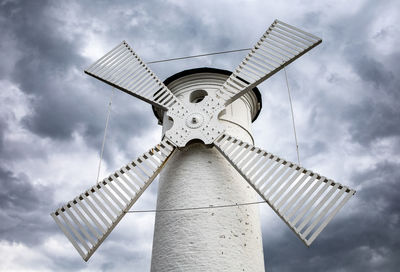 Low angle view of traditional windmill against cloudy sky