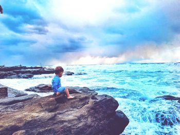 Boy standing on beach against sky