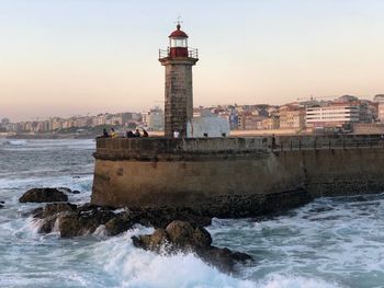 View of lighthouse by buildings in city