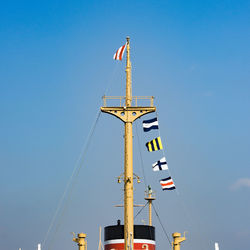 Low angle view of crane against clear blue sky