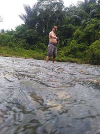 Full length of shirtless man standing in river