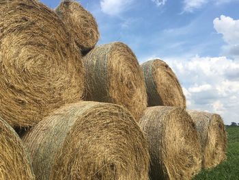 Stack of hay bales on field against sky