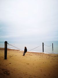 Rear view of man walking at beach against sky