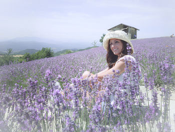 Portrait of woman with purple flowers on field