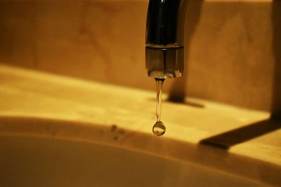 Close-up of water drop from faucet in bathroom