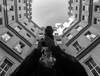 Low angle view of man photographing buildings in city