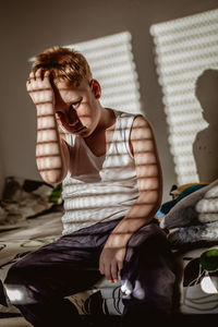 Young woman sitting on bed at home