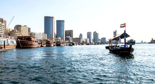 Nautical vessel on river by buildings in city against clear sky