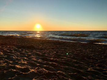 Scenic view of beach against clear sky during sunset