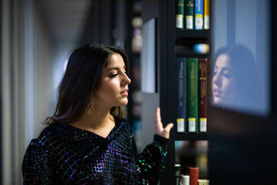 Young woman looking away while standing in library