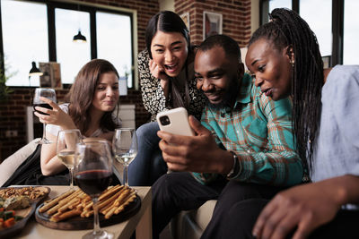 Portrait of friends using mobile phone while sitting at restaurant