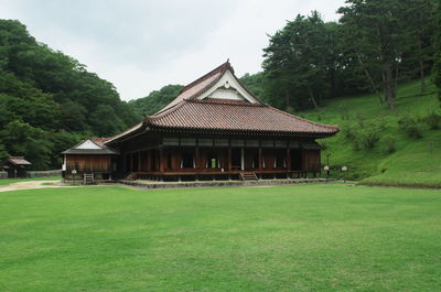 House on field by trees against sky