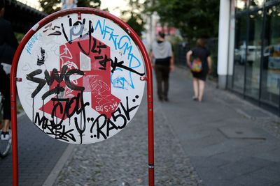 Close-up of sign with people walking in background