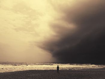 Person standing at beach against sky