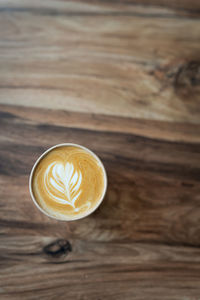 Cappuccino coffee with pattern on foam in eco glass on table favorite coffee cup concept