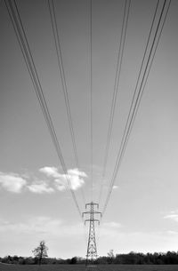 Low angle view of electricity pylon against cloudy sky