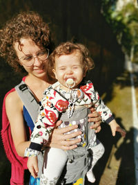 Modern mother carrying her baby in the sling during summer