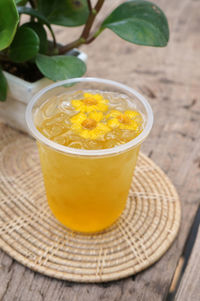 Chrysanthemum tea or cool chamomile tea in a glass placed on a wooden table.