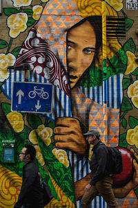 Man standing by graffiti on wall