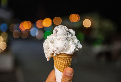 Personal perspective night photo of hand holding ice cream in cone