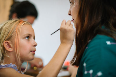 Portrait of daughter doing makeup to mom