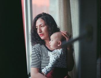 Mother and daughter against window