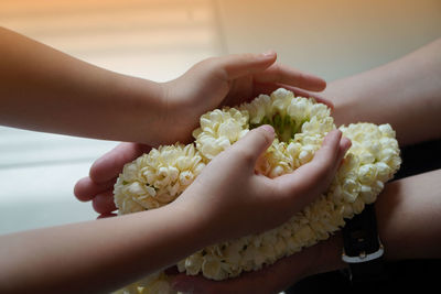 Cropped hand of people holding floral garland