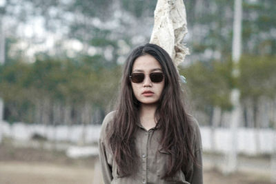 Portrait of young woman standing against tree