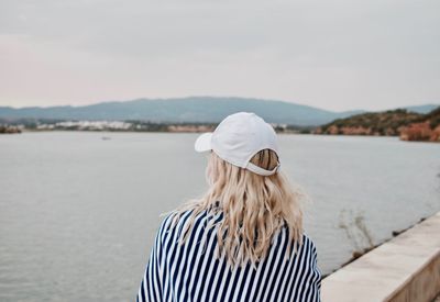 Rear view of woman standing by sea against sky