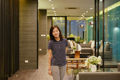 Portrait of woman standing in illuminated hotel room