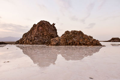 Rock formations on beach against sky