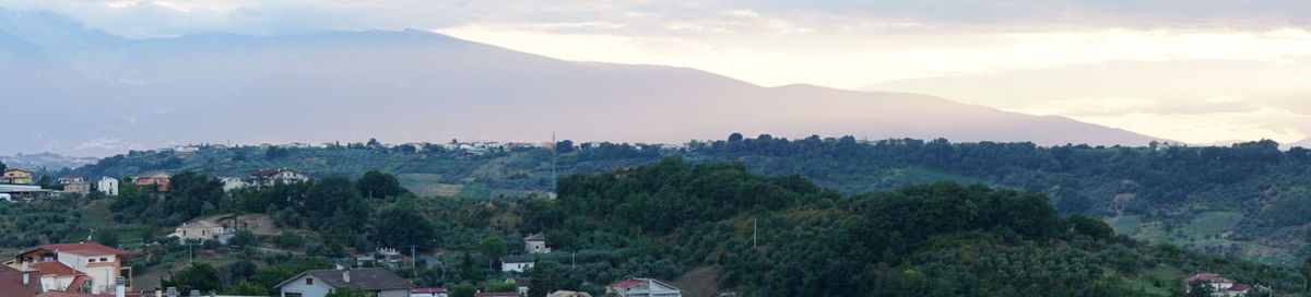 Panoramic shot of trees and cityscape against sky