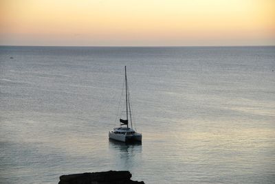 Sailboat on sea against sky during sunset