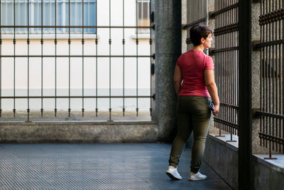 Full length of young woman standing against railing