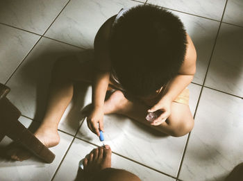 High angle view of son applying nail polish to mother at home