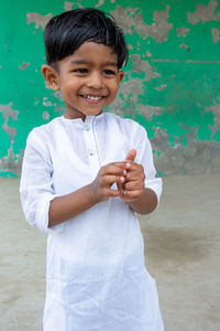 Portrait of smiling boy standing against wall
