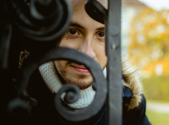 Young guy portrait hiding behind a metal fence - copy space