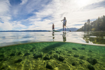 A man and woman stand up paddle boarding on lake tahoe, ca