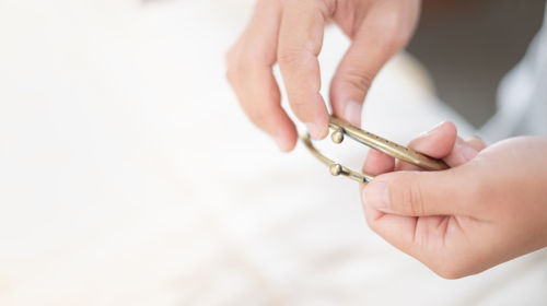 The female hand choosing two types of purse clasp that showing the perforated metal frame with bead.