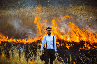 Portrait of man standing on field against bonfire