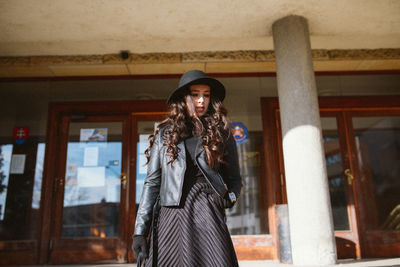 Portrait of young woman standing in front of building